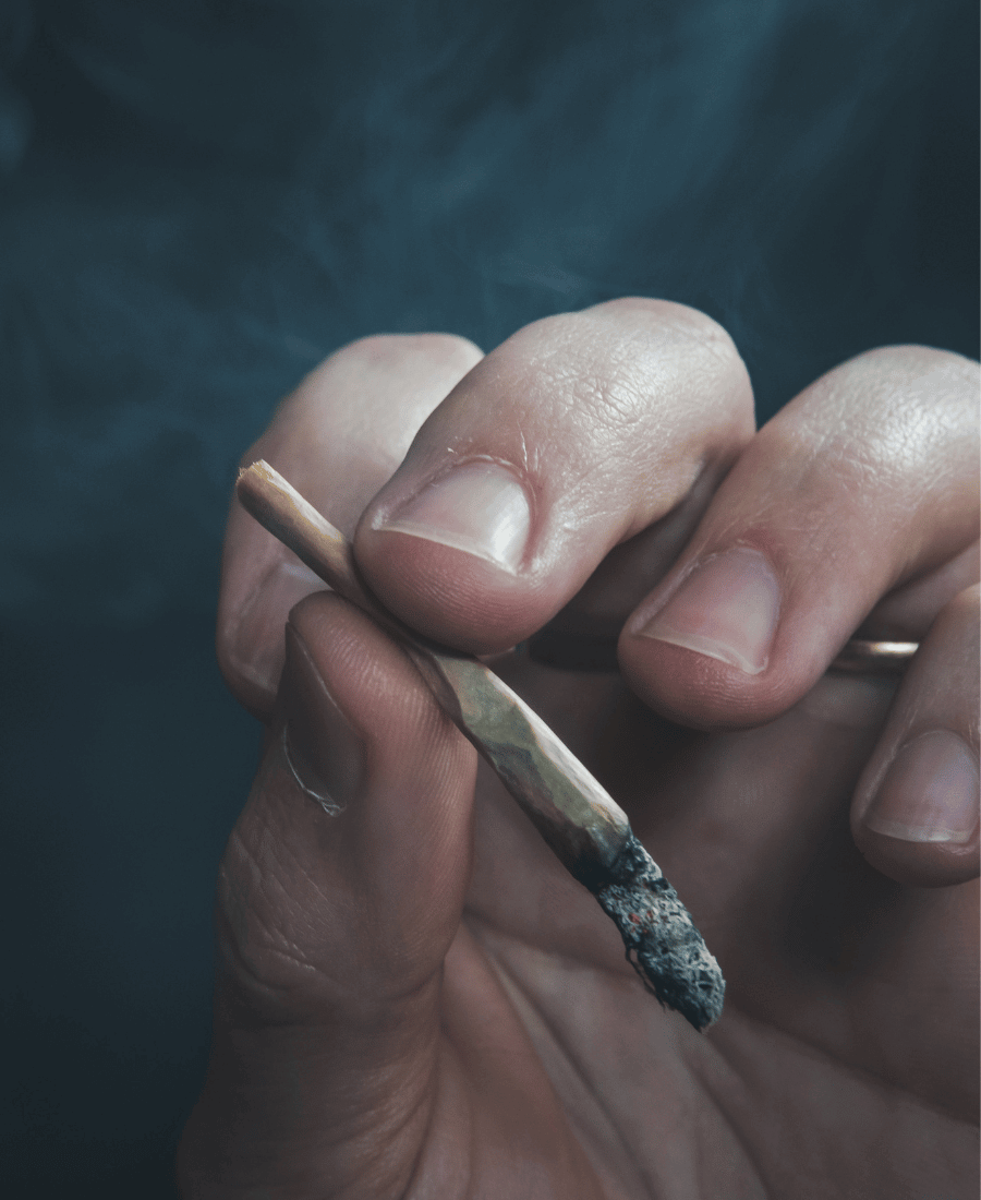 Hand hält glimmenden Cannabis Joint